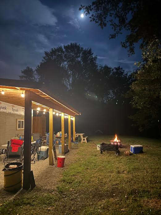 Moonlit night with campfire and poker under the shanty roof.