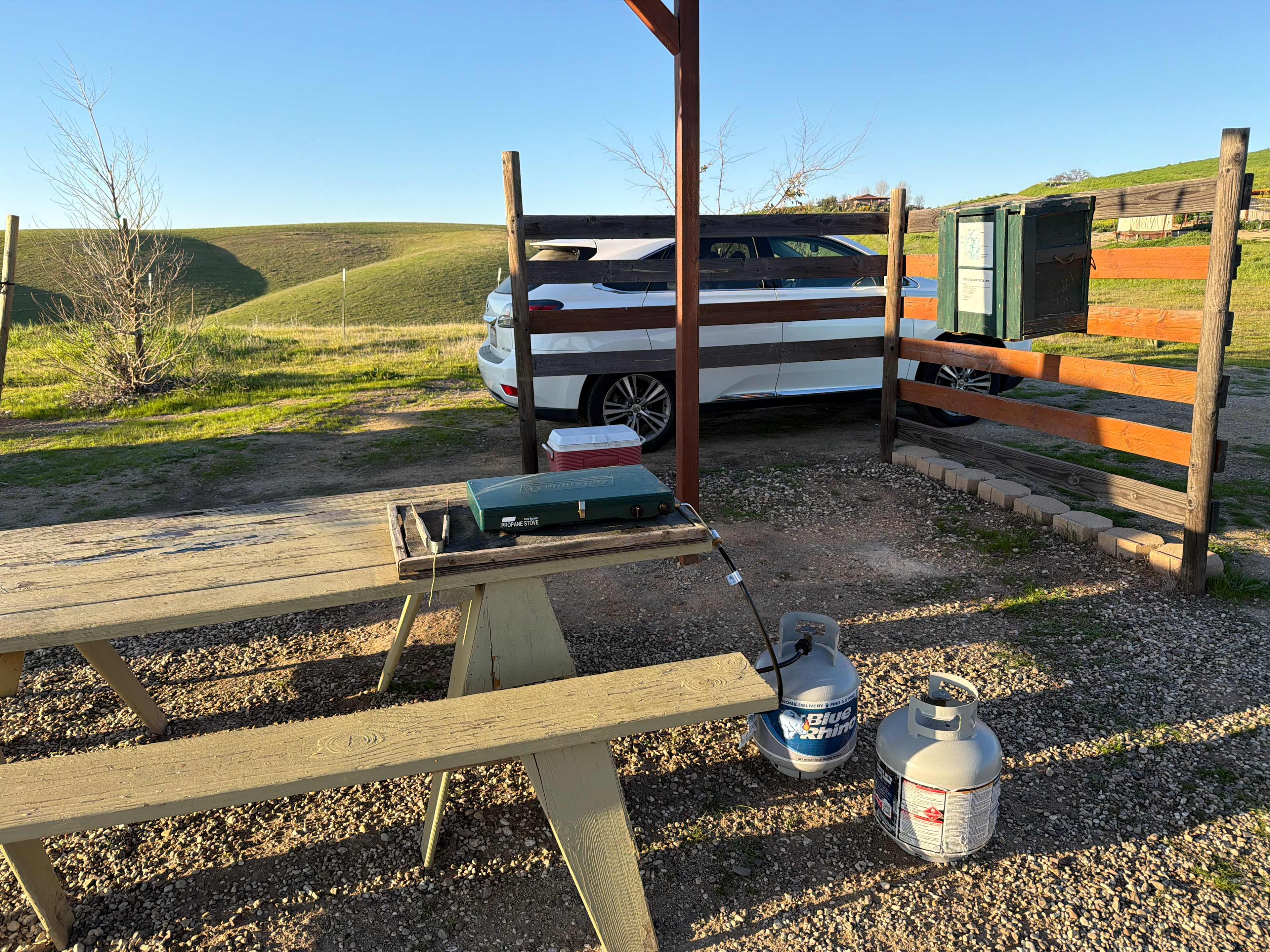 Coyote Flats (cooking area- 2 burner camping stove with propane tanks, cooler in background available for guests to use, and the green box hanging on the fence is stocked with cooking supplies!))