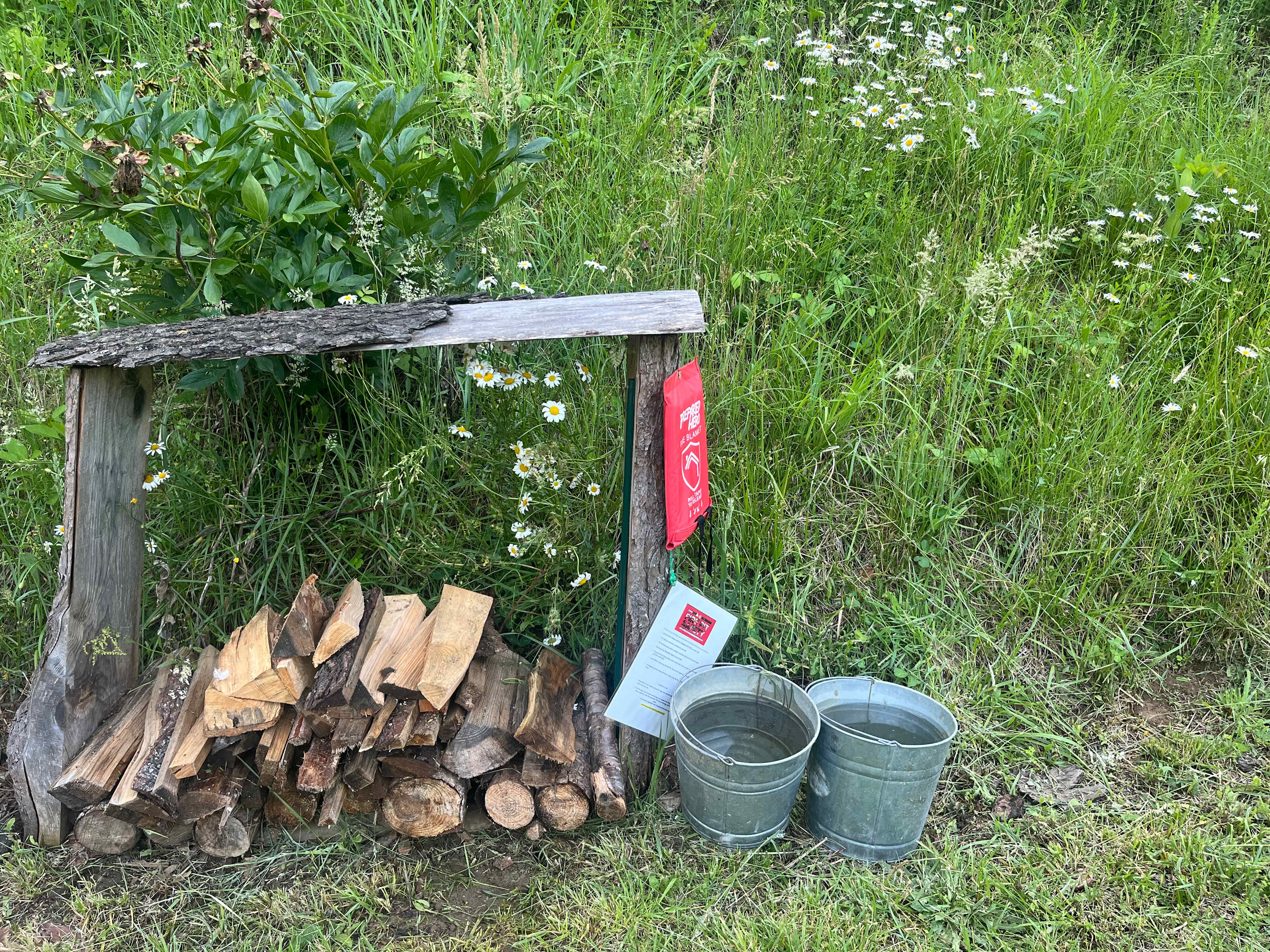 Firewood provided. As well as safety precaution notes, a fire extinguisher, two buckets of water to put out the fire at the end of the night! (firewood set & ready to be lit in fire pit ~ not pictured.)