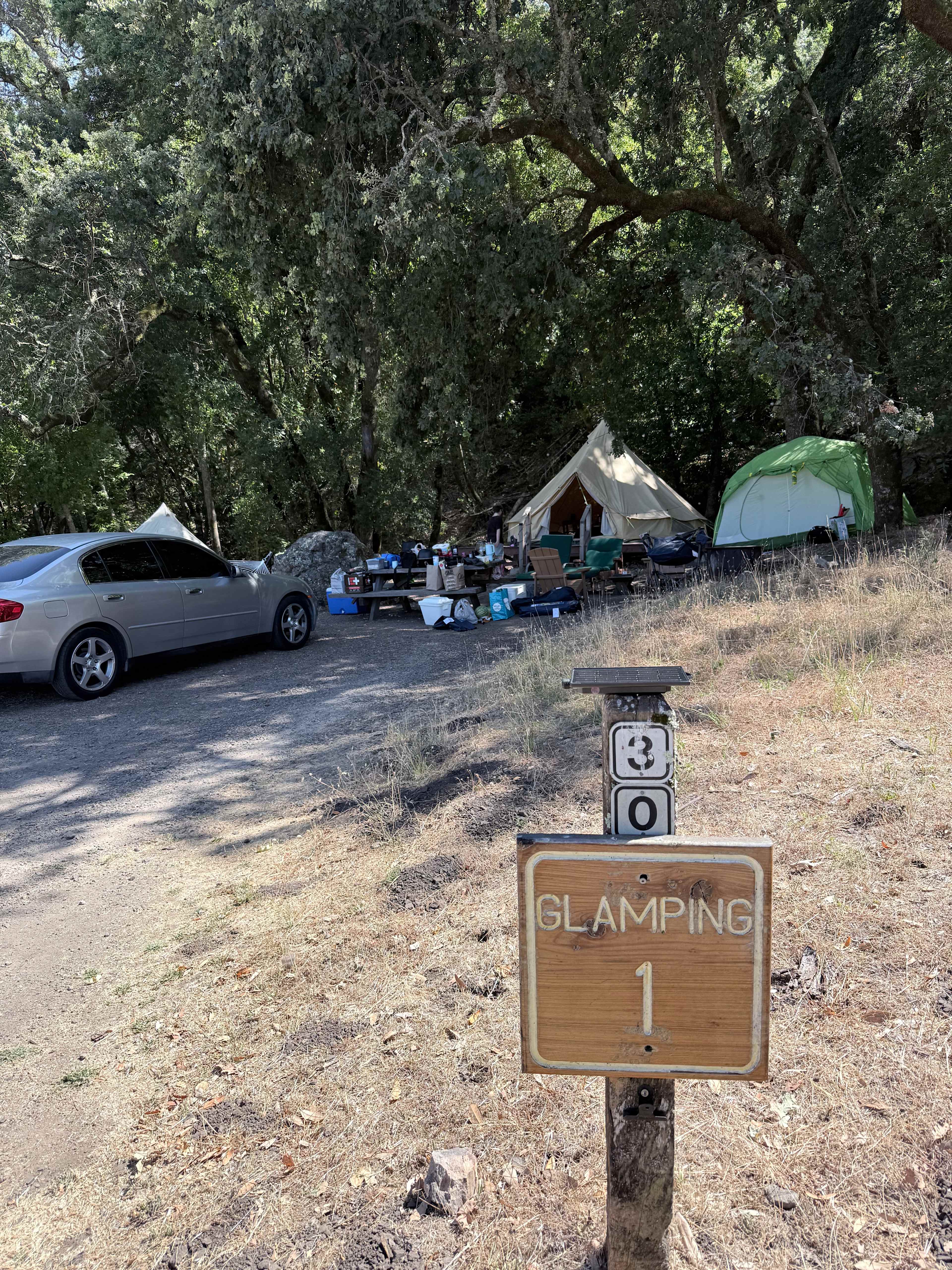 Glamping site number 1, which is on camping spot number 30 on the map. Late morning sun, with shade in evening and cooled off nights from being under the canopy of trees, and fern and moss covered rocks and boulders within the trees and hill behind camp.