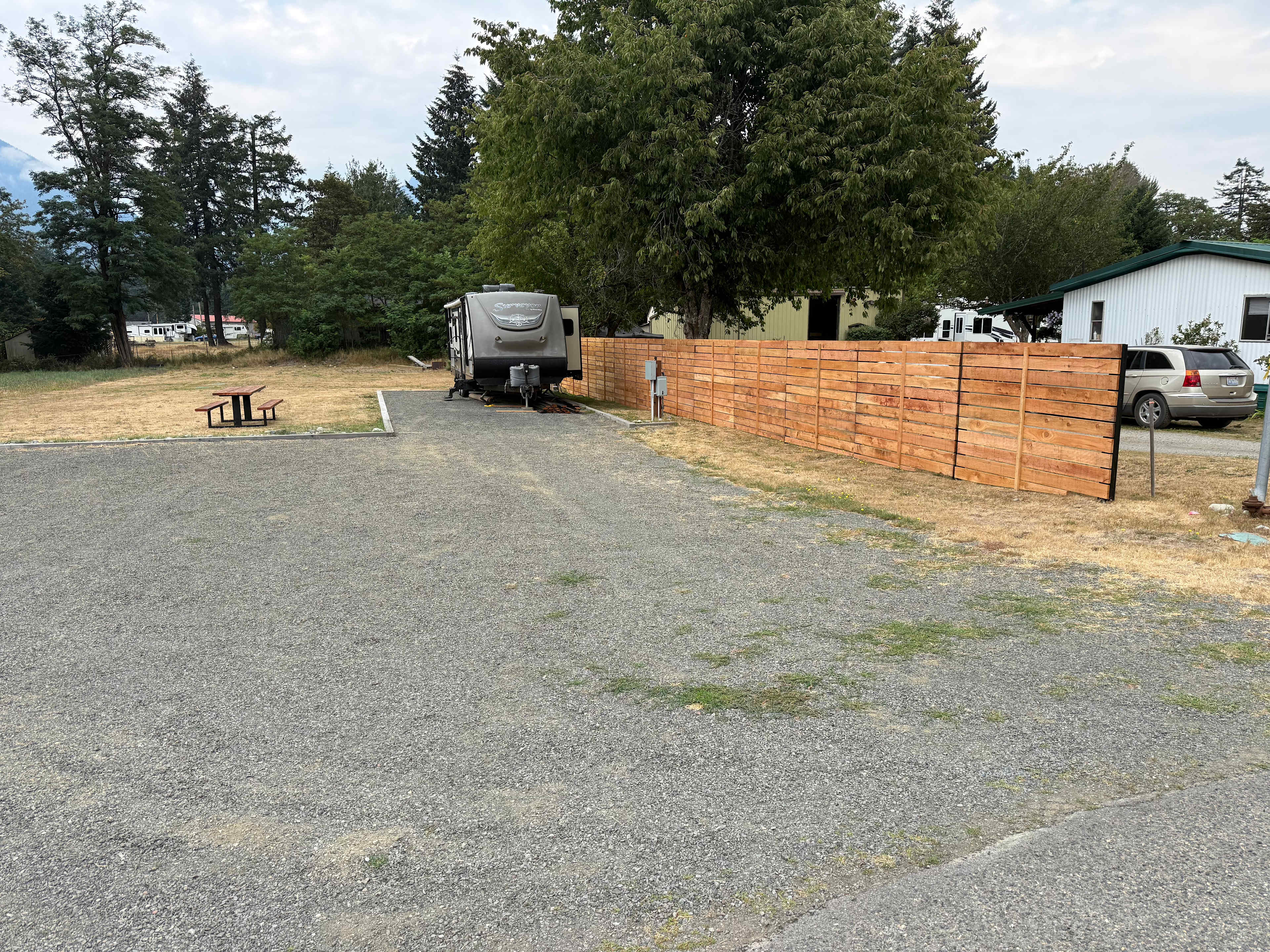 View from Edmonds Rd.  Our RV is pictured and often in place through the summer season.  Site A is in front of our RV along the cedar fence. Longer setups (over 35’ w/4 door truck) may need to disconnect pull vehicle after setup to avoid being in the street. 