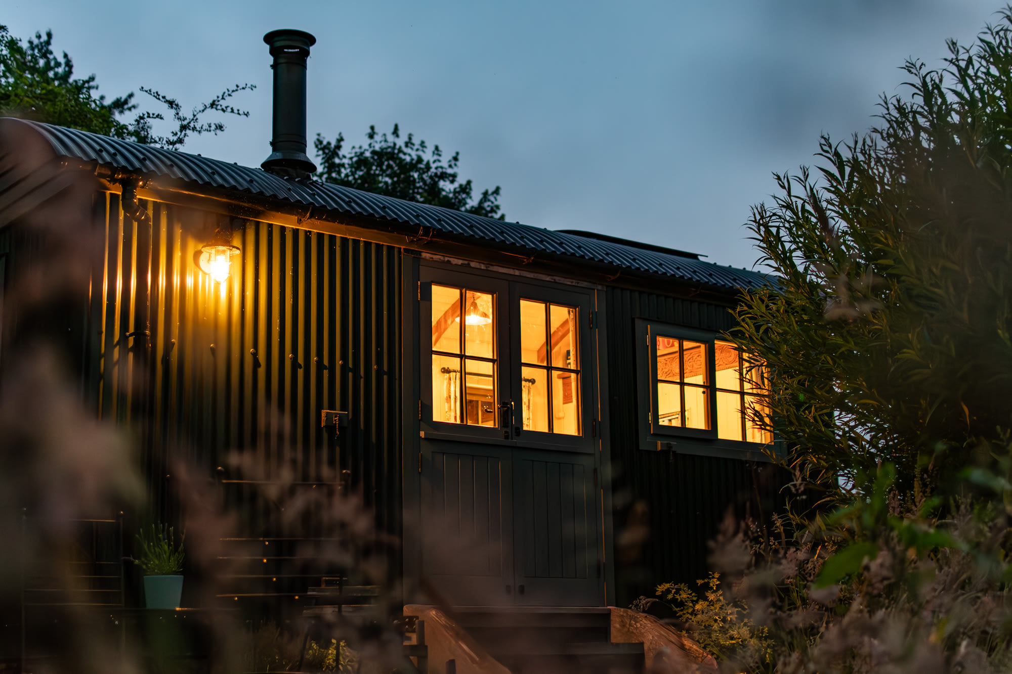 An outside view of the warmly lit hut at dusk