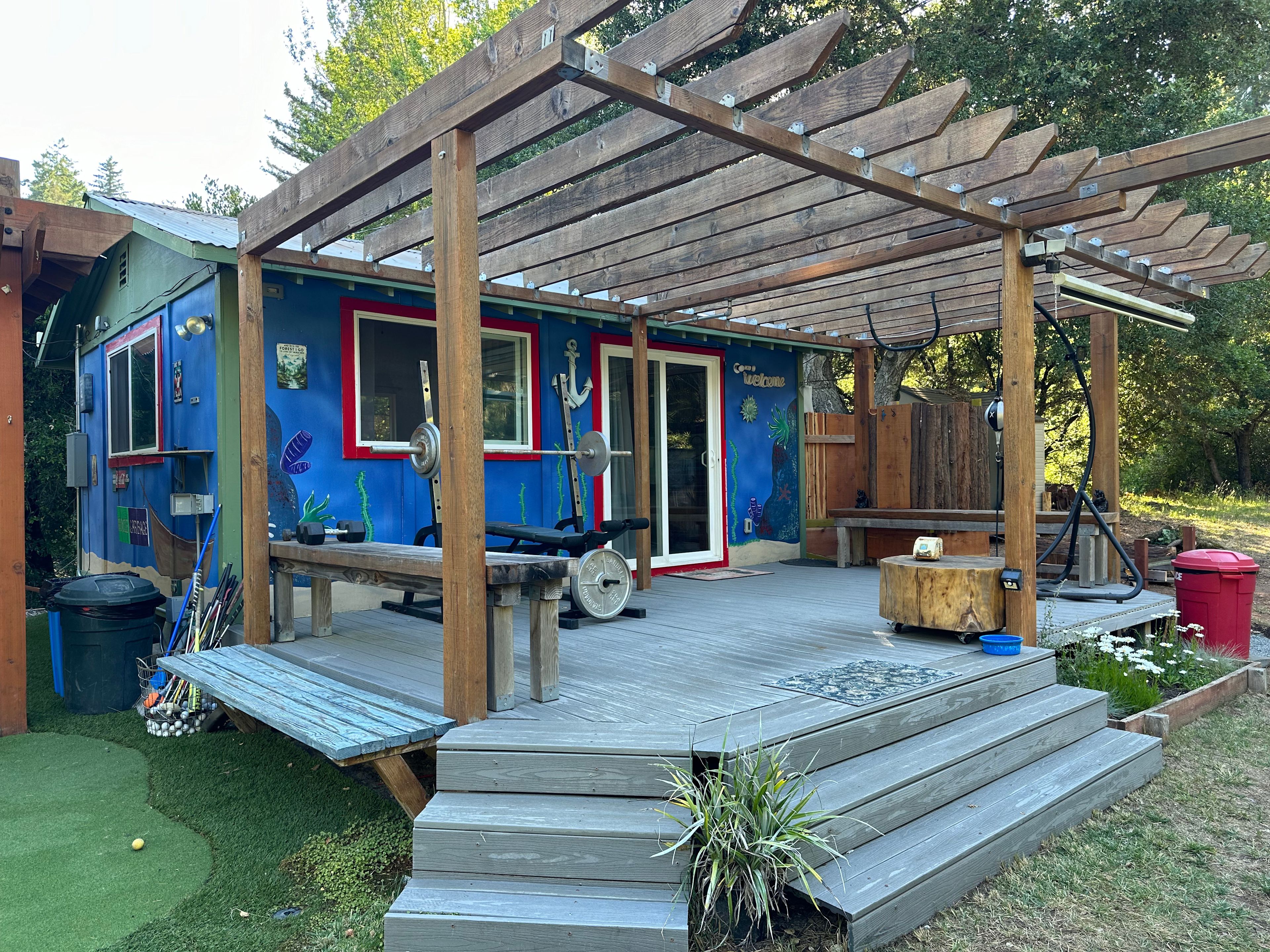 Bungalow porch with weight bench, punching bag, pull-up bar and shower. 