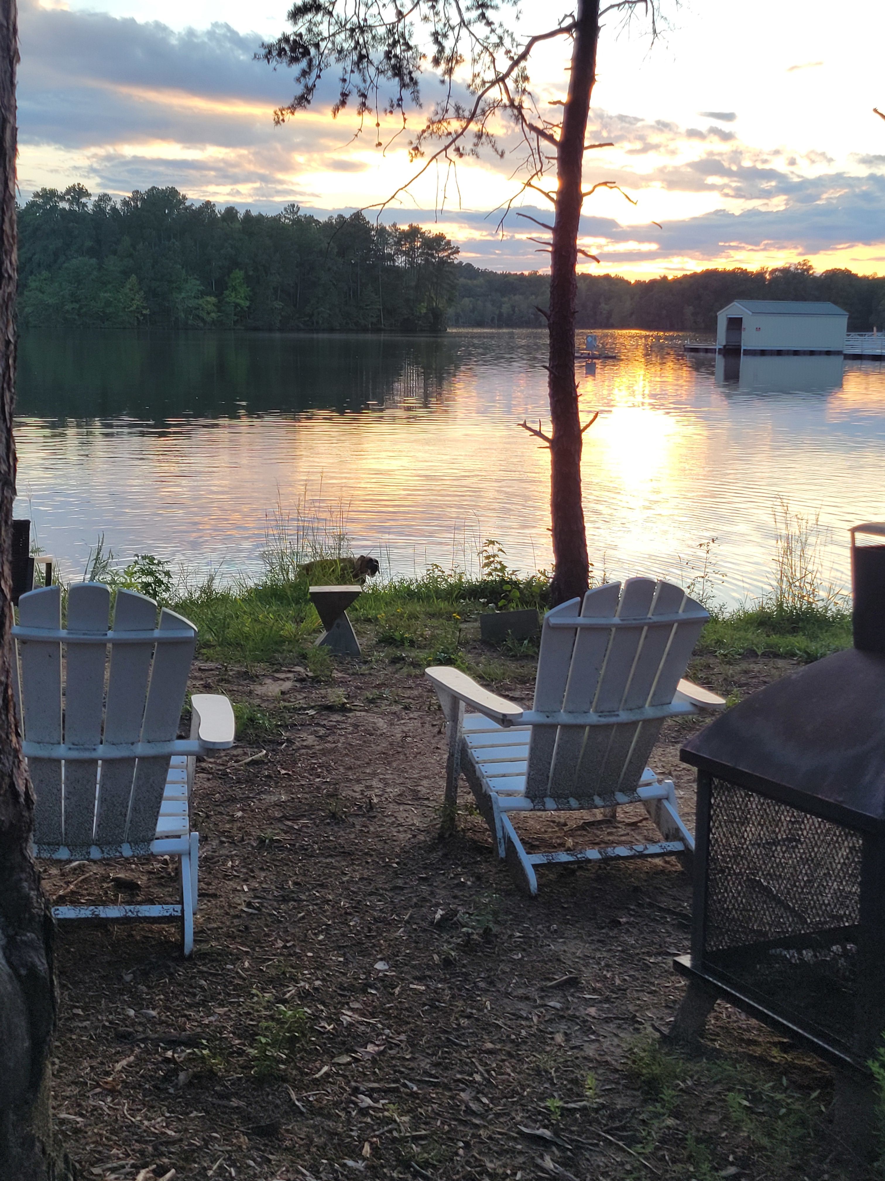Chairs, fireplace, table, and seasonal gazebo are located by the lake. 
