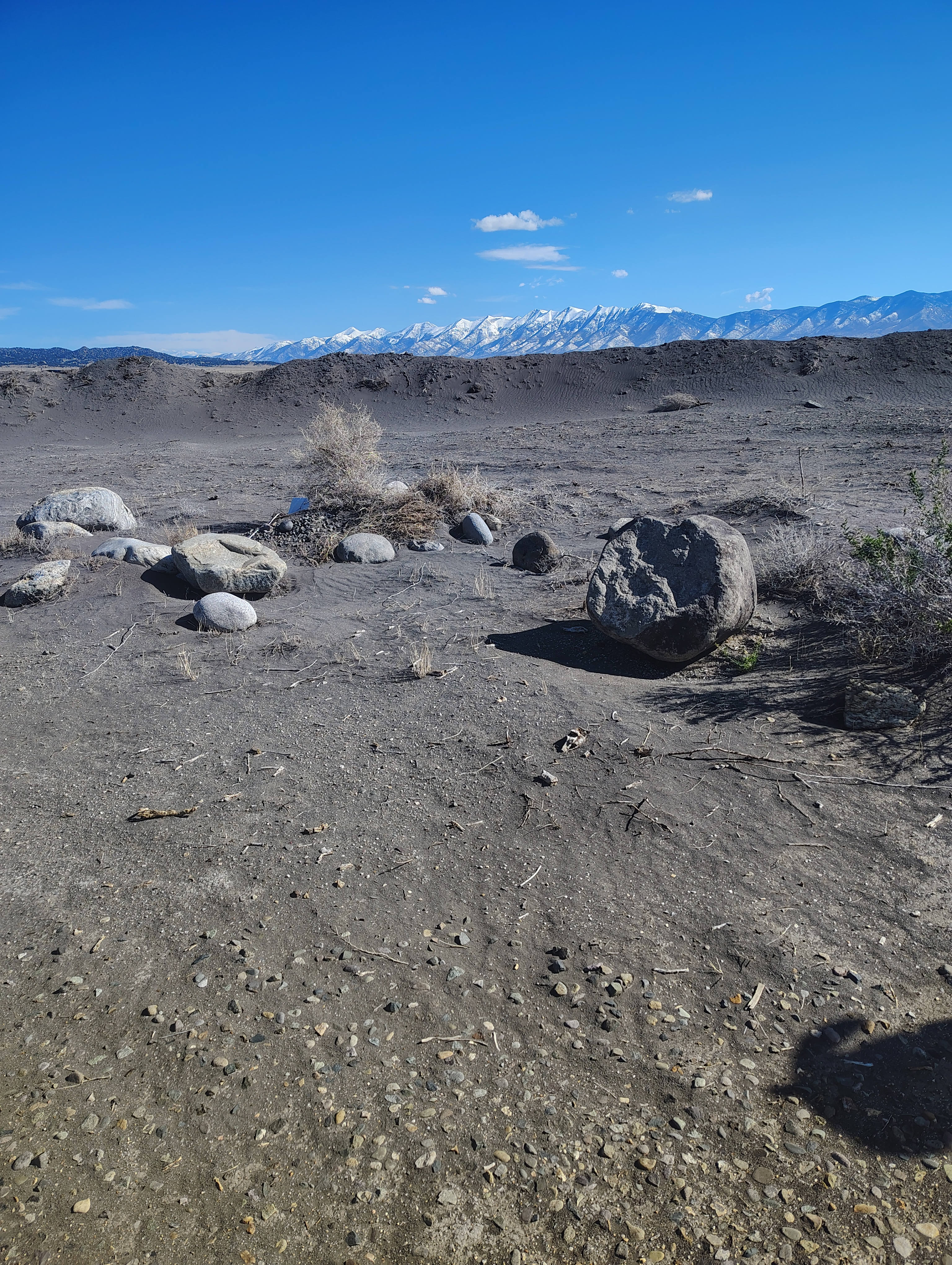 The terrain is uneven. It is a mixture of rocks, dirt and sand.