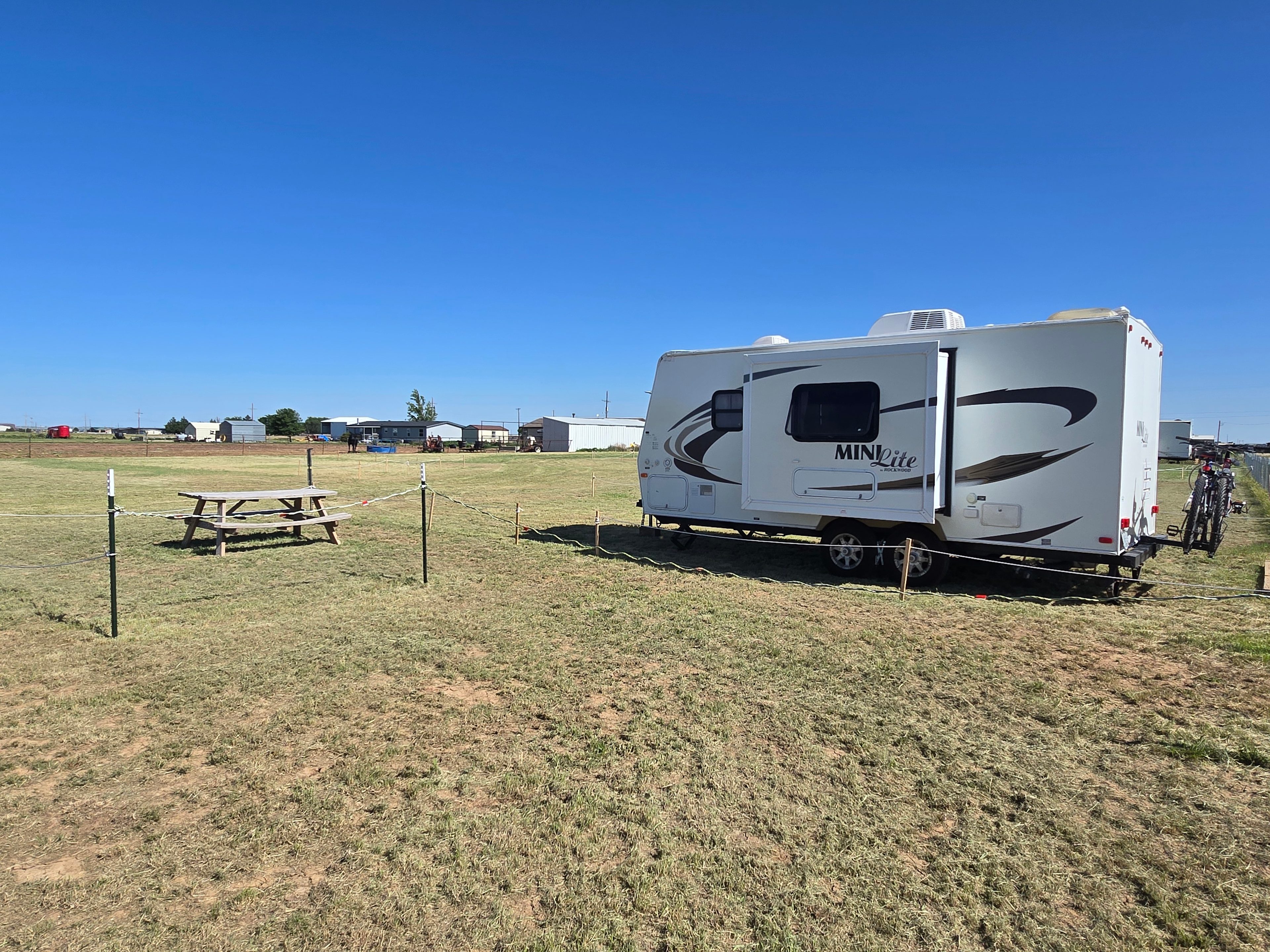 Site D, RV back- in site with horses in the background 