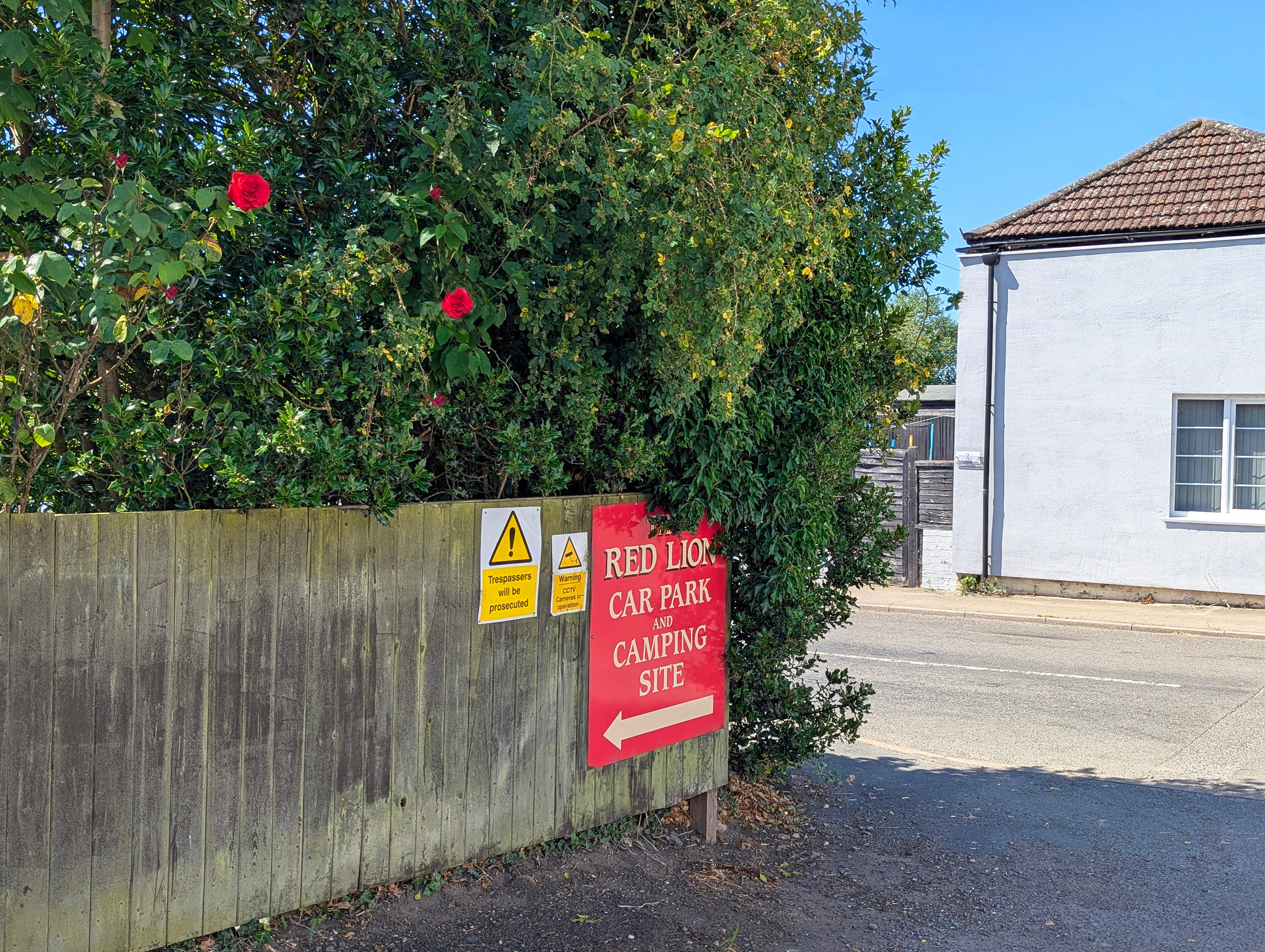 Entrance signage from the roadside with a shop immediately over the road and pub adjacent, both under ownership of the campsite.