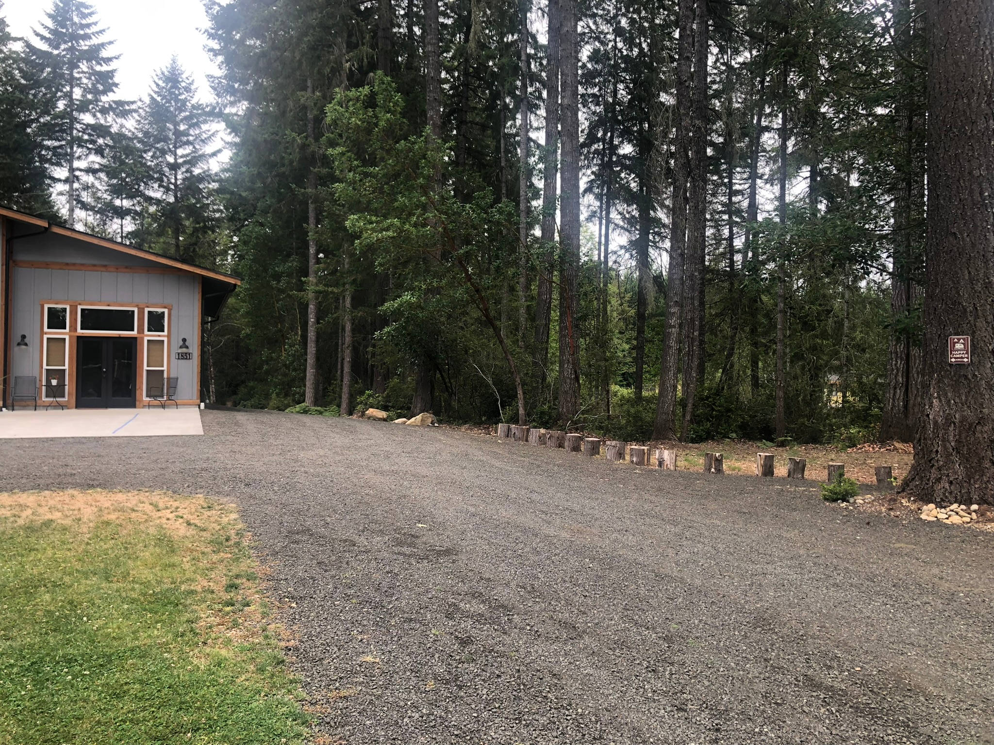 View of the apartment on left (w/ 2 bedrooms, bathroom and kitchen). View of tent site on right (row of stumps around tent site).