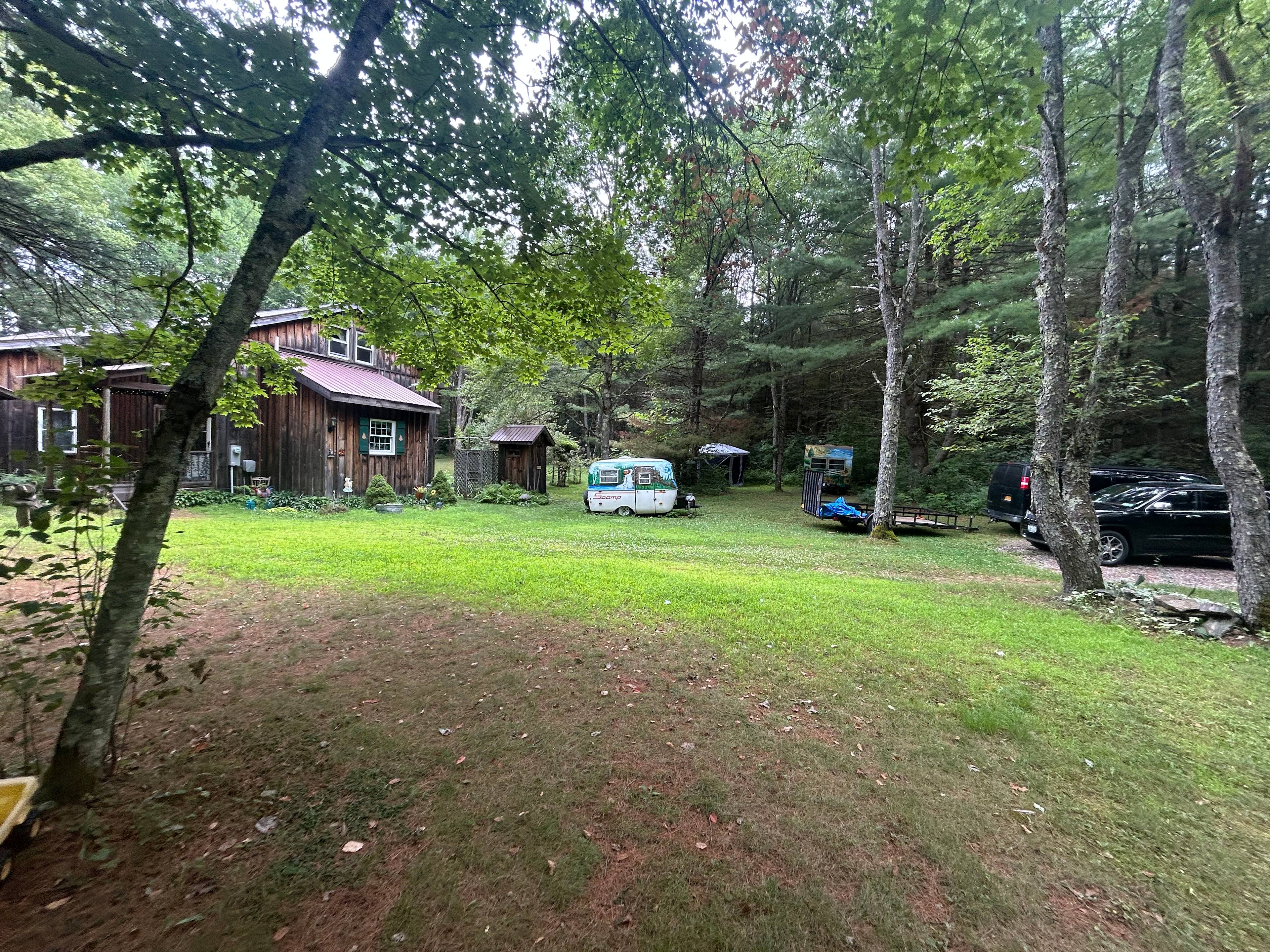 House relative to the camper, which can be seen back against the tree line sort of in the shadows (is not the small scamp in the light)