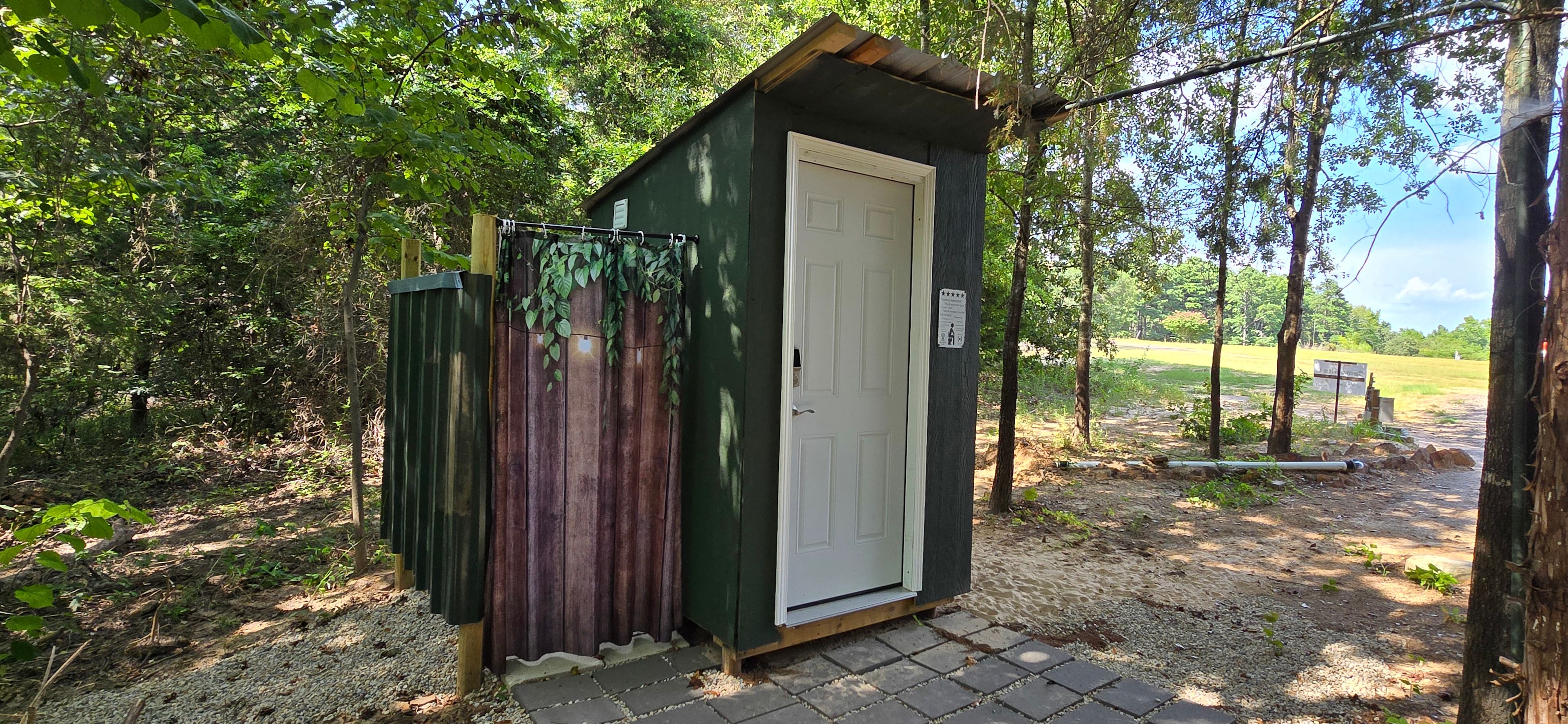 Toilet and sink with outdoor shower behind Site C. For use by sites A, B, and C with a code.