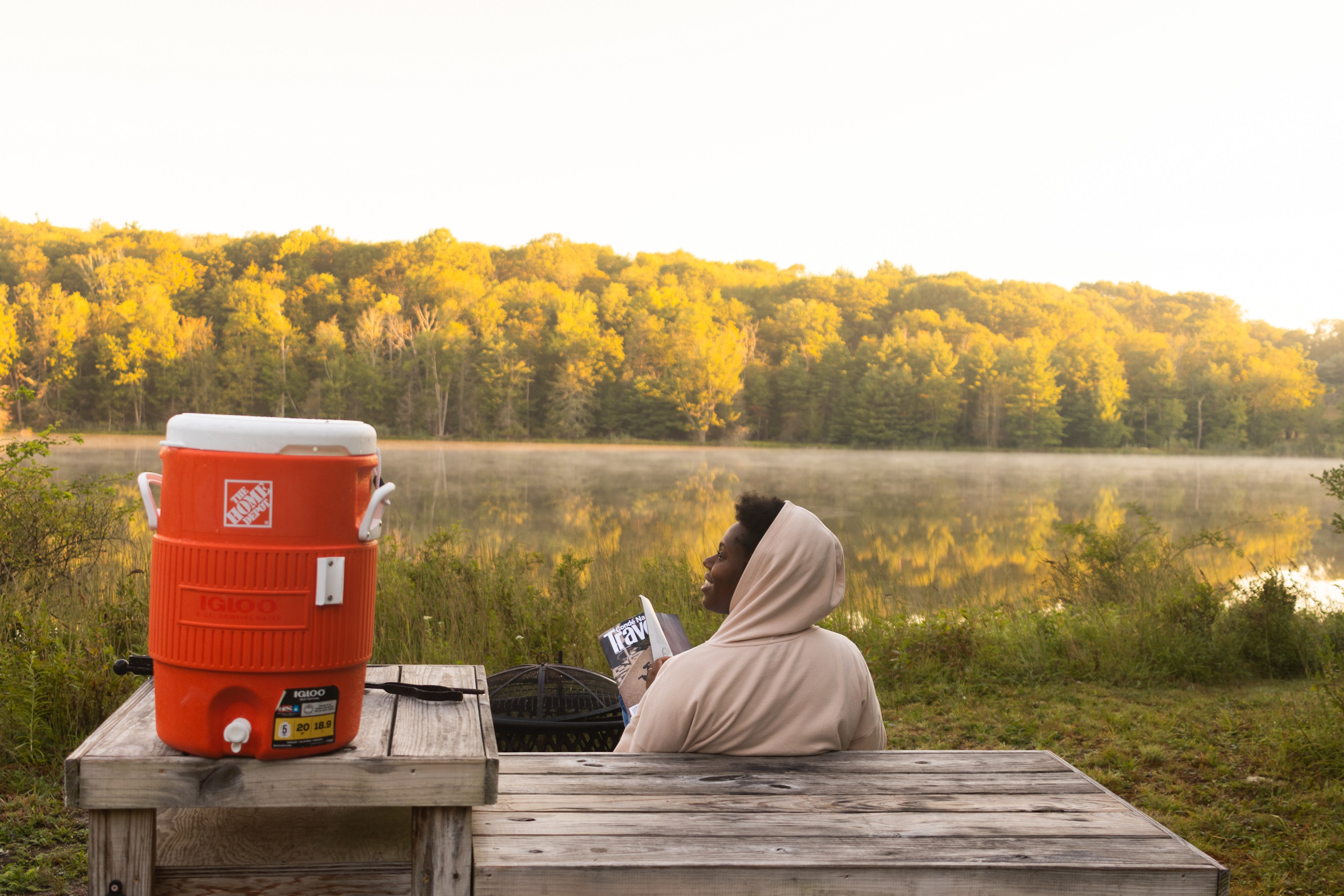Reading a magazine as the sun rises on the picnic table just outside of our tent