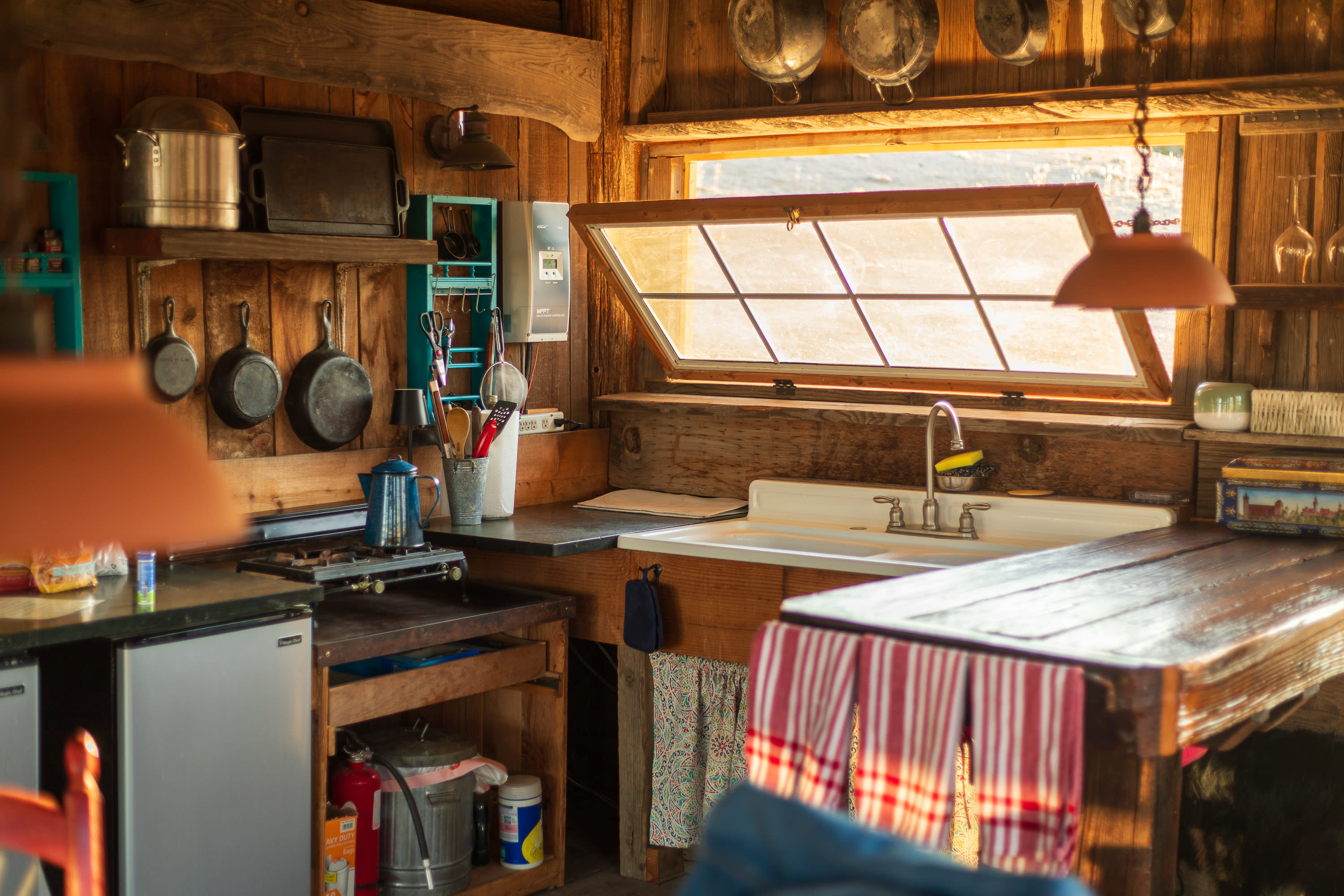 Kitchen complete with sink, mini fridge, double burner, garbage, and pans/cooking tools/etc.