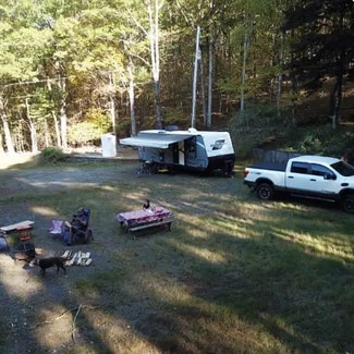 Guest's RV and vehicle hooked up with picnic table and chairs. 
