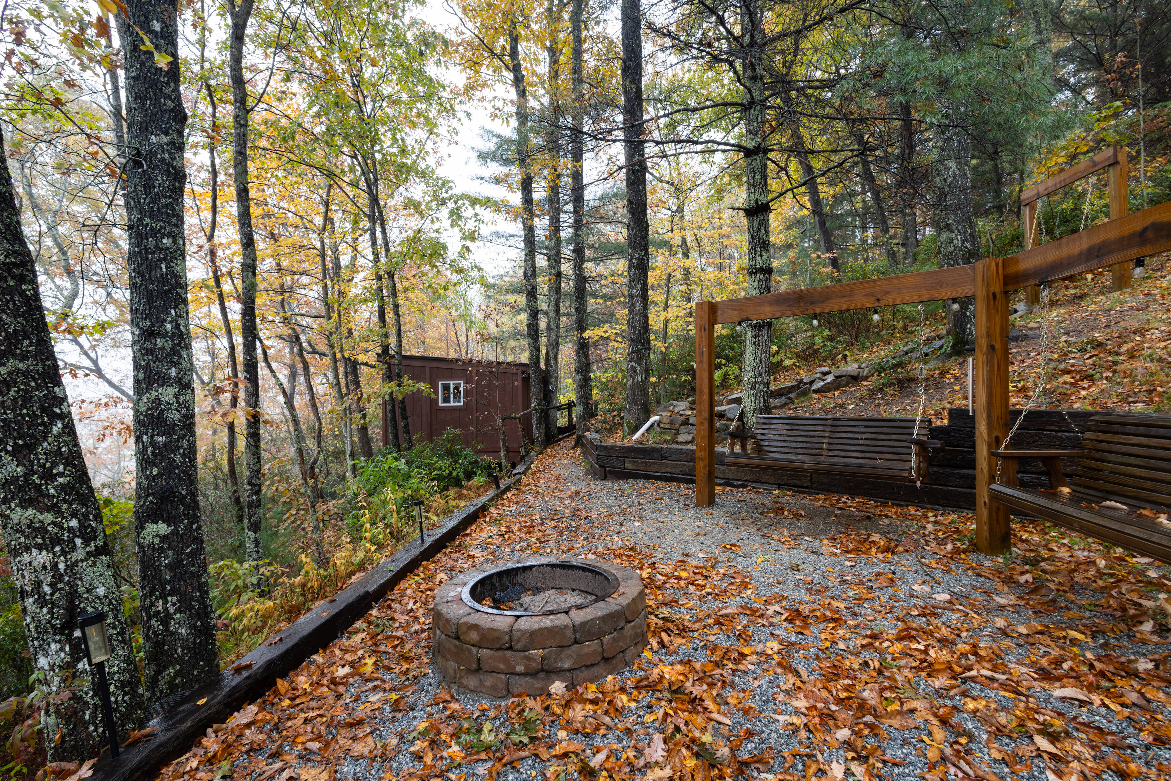 Fire pit area with swinging benches to the side of the cabin.