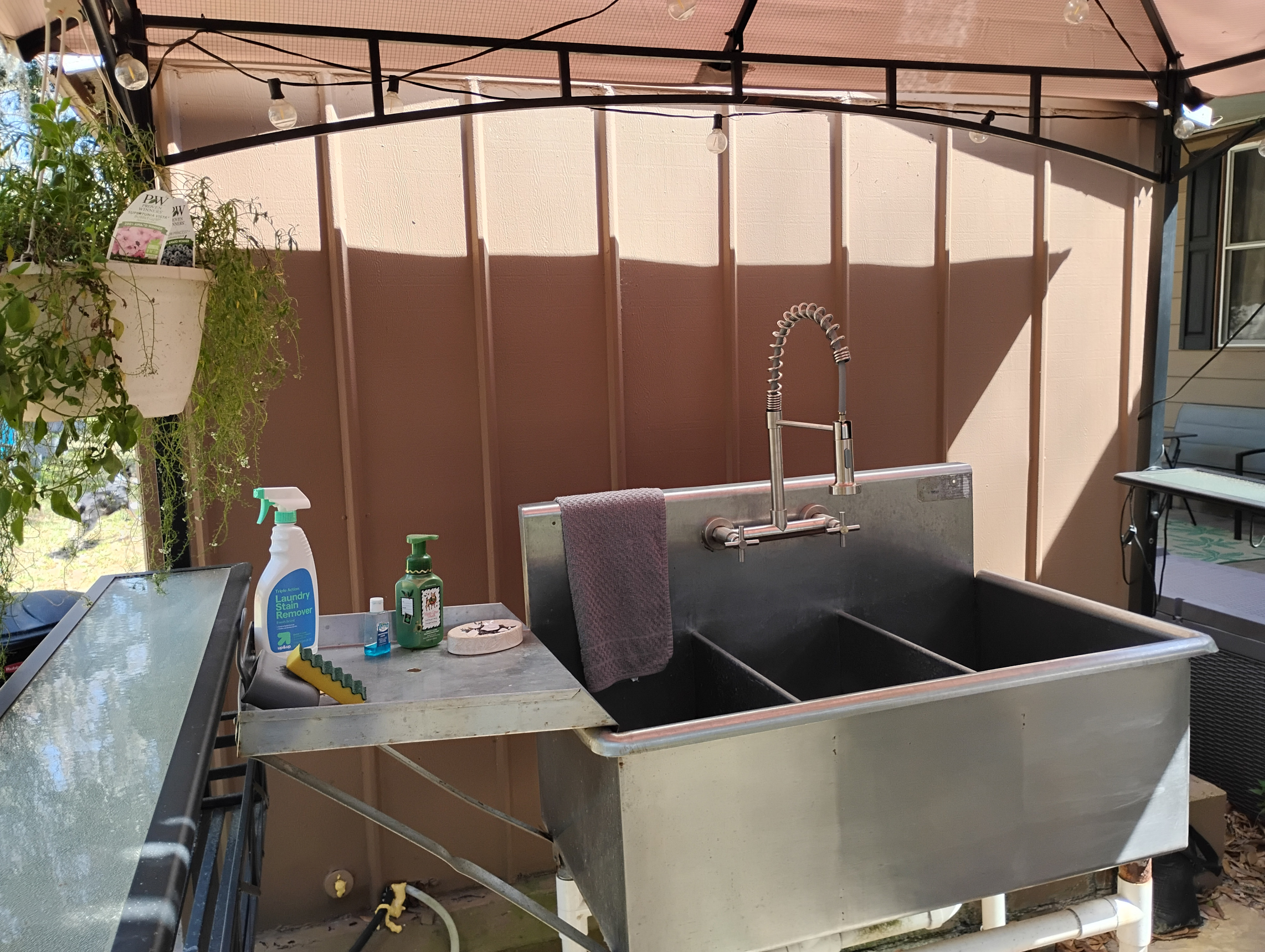 Outdoor sink with Spray Faucet and 4 gallon hot water heater located under lighted gazebo cover.