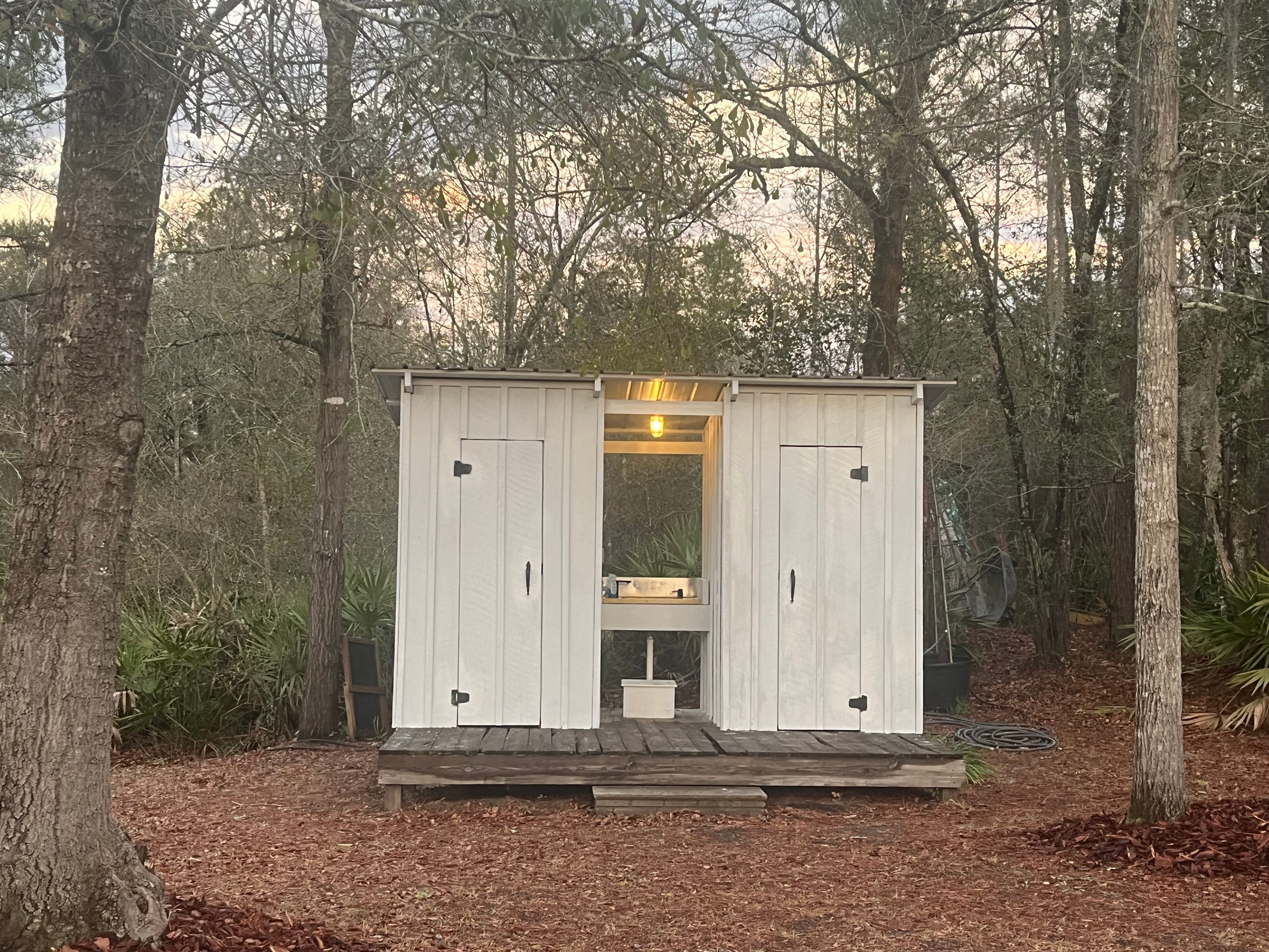 Outhouse-style bathroom with electric and a hand wash sink