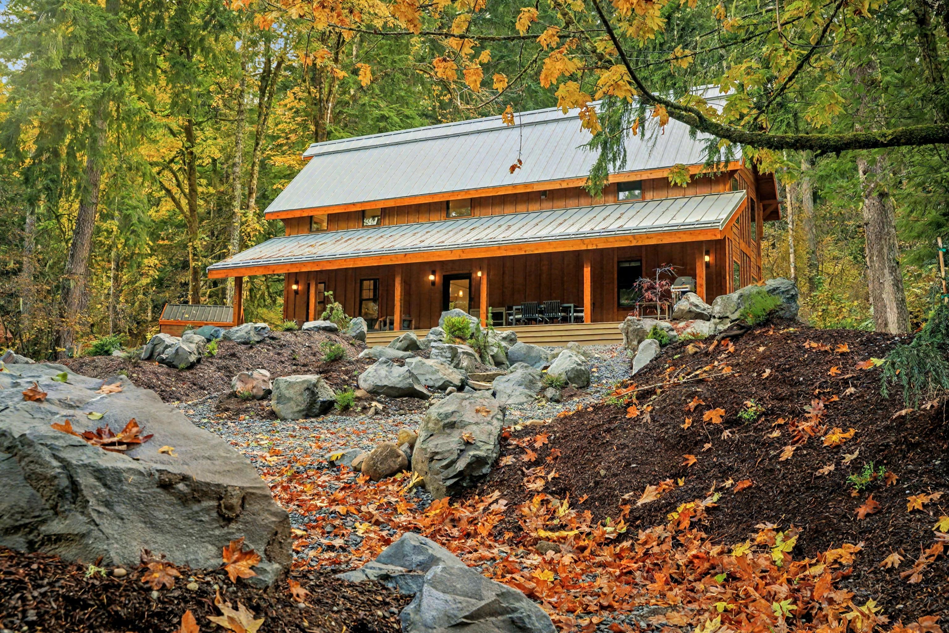 The cabin set against a canopy of fall foliage, showing the full length of the structure tucked naturally into the tree line.