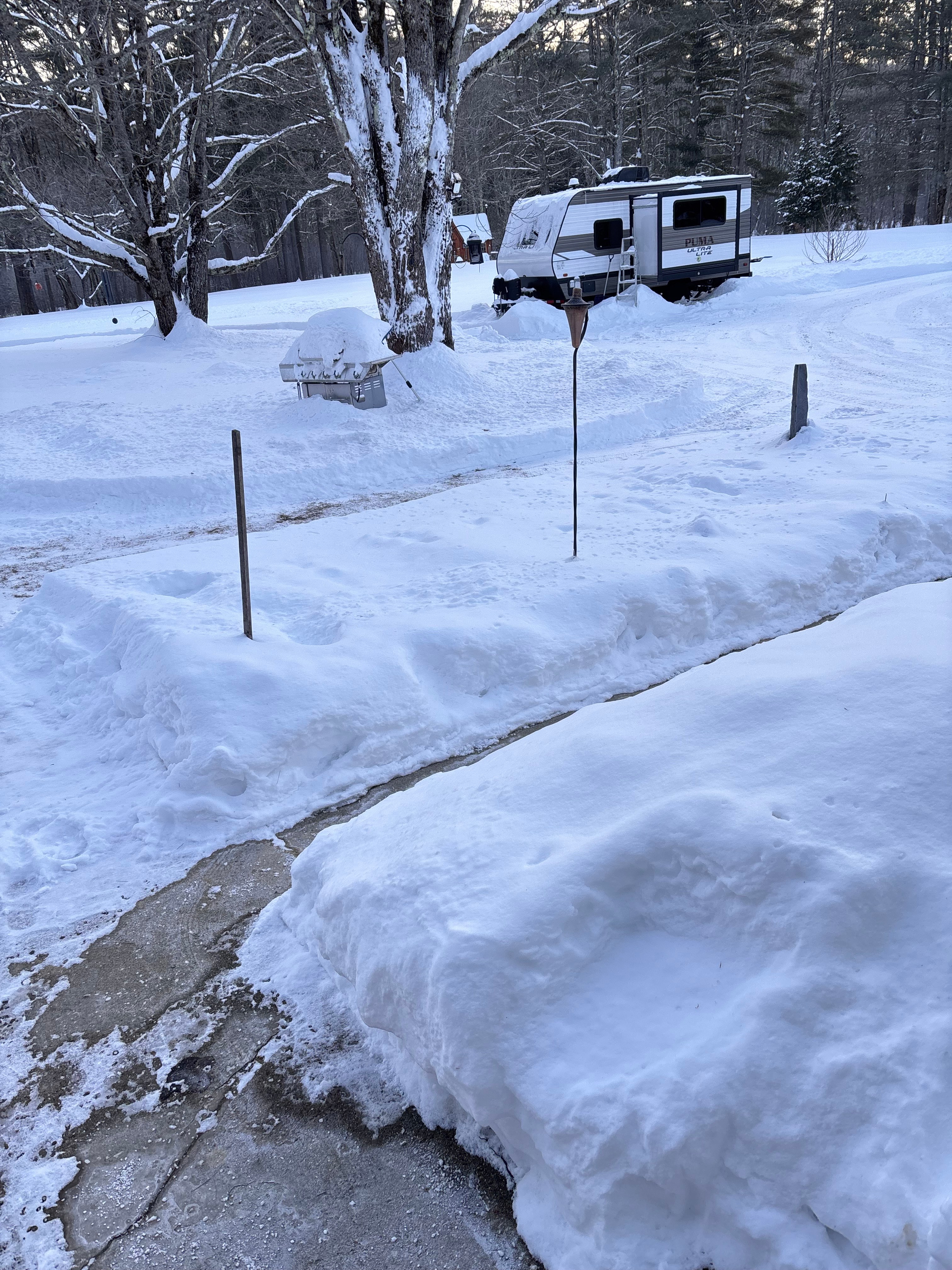 "Winter in New Hampshire: Even after a major storm, our gravel turnaround stays plowed and passable. This shot shows the edge of the cleared loop leading to the snow-covered open field—proving our site is ready for year-round adventure."