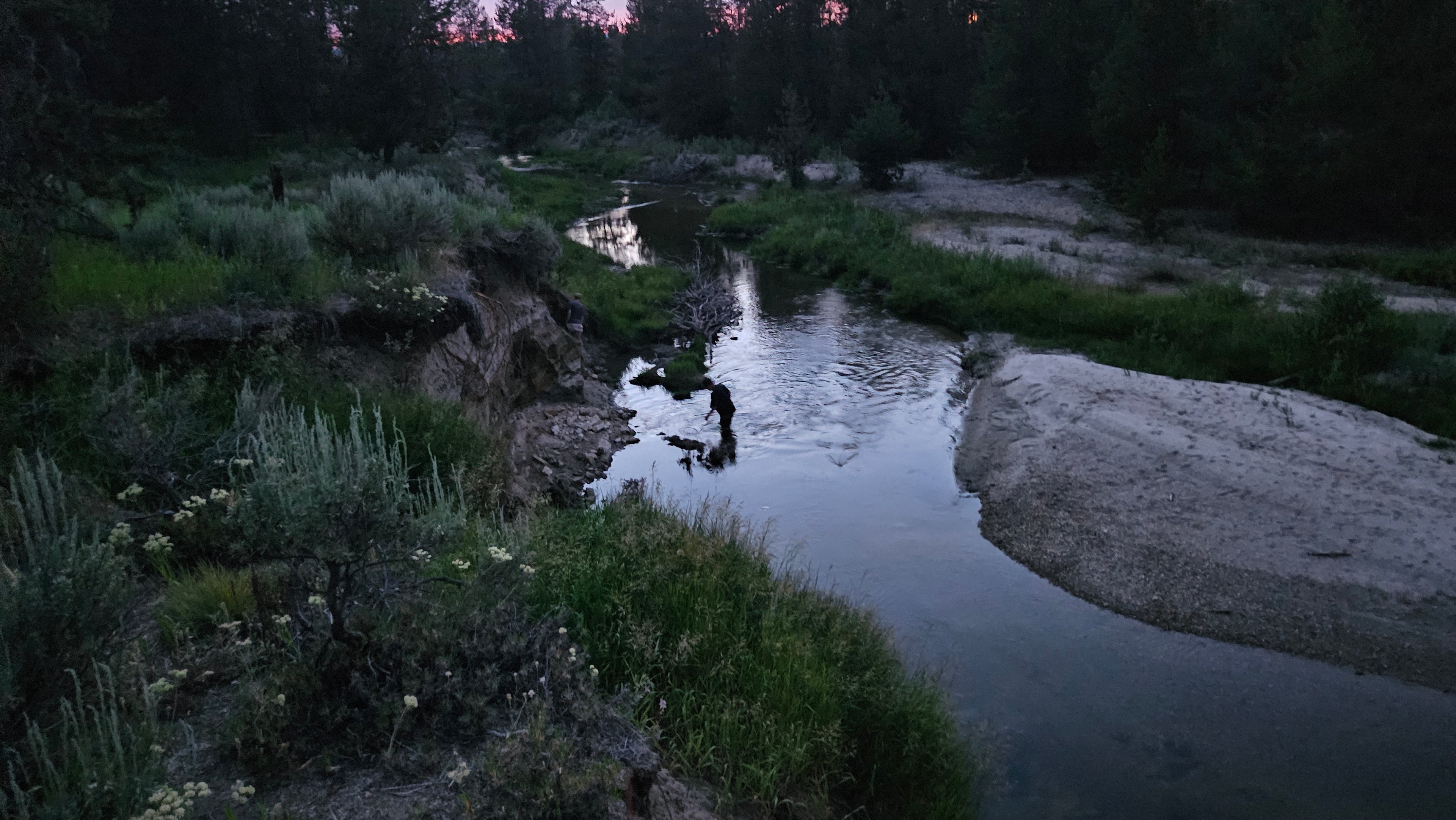 Vibrant purple and pink sunset skies reflecting over the creek, creating a colorful, peaceful evening backdrop across the water and surrounding landscape.