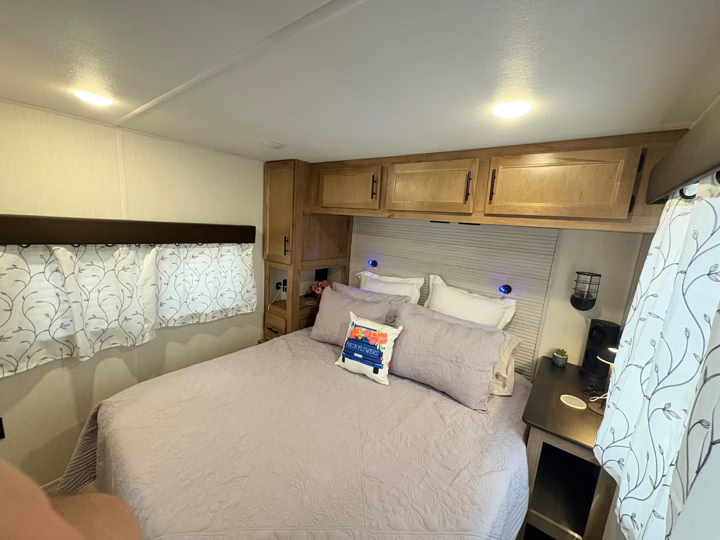 Master bedroom with curtains closed.  Storage above and beside the bed.