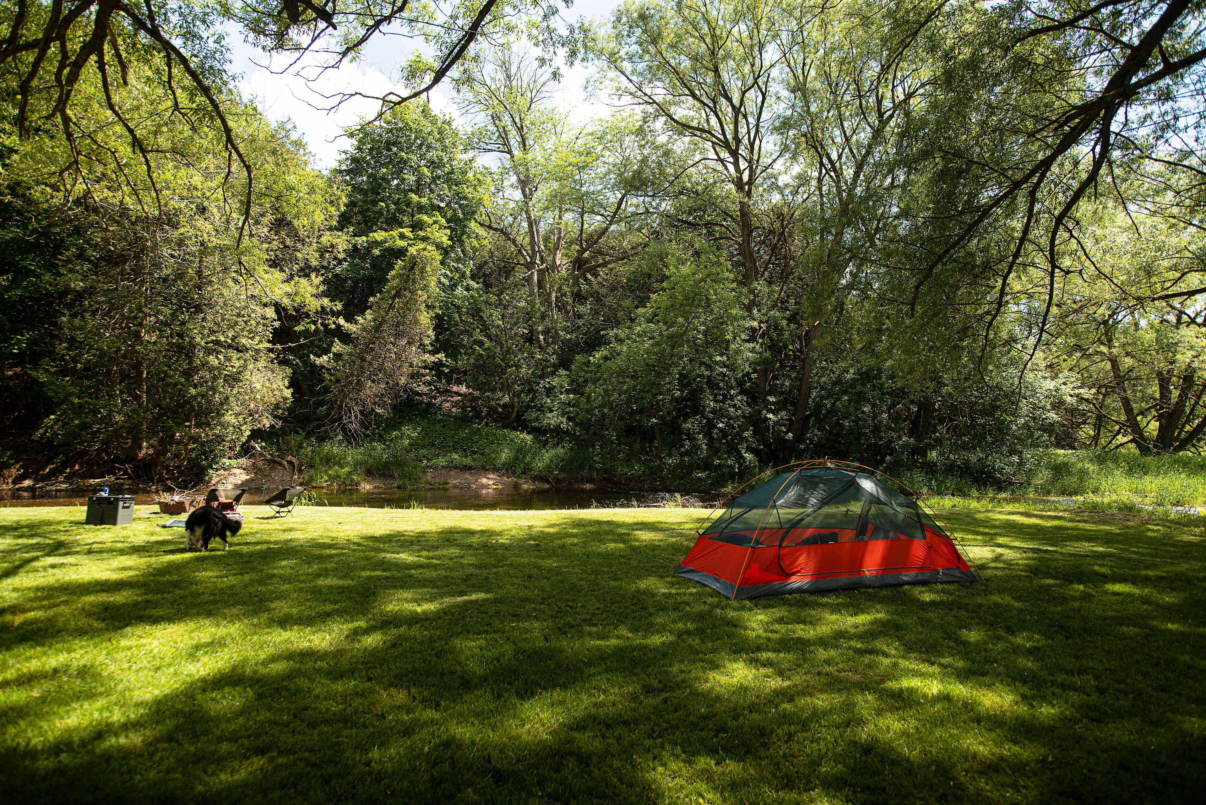 Overlooking site, tent, river, and fire pit.