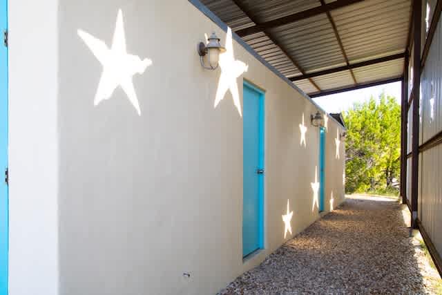 Bath house with four private bathrooms that have shower, toilet, sink and fan.