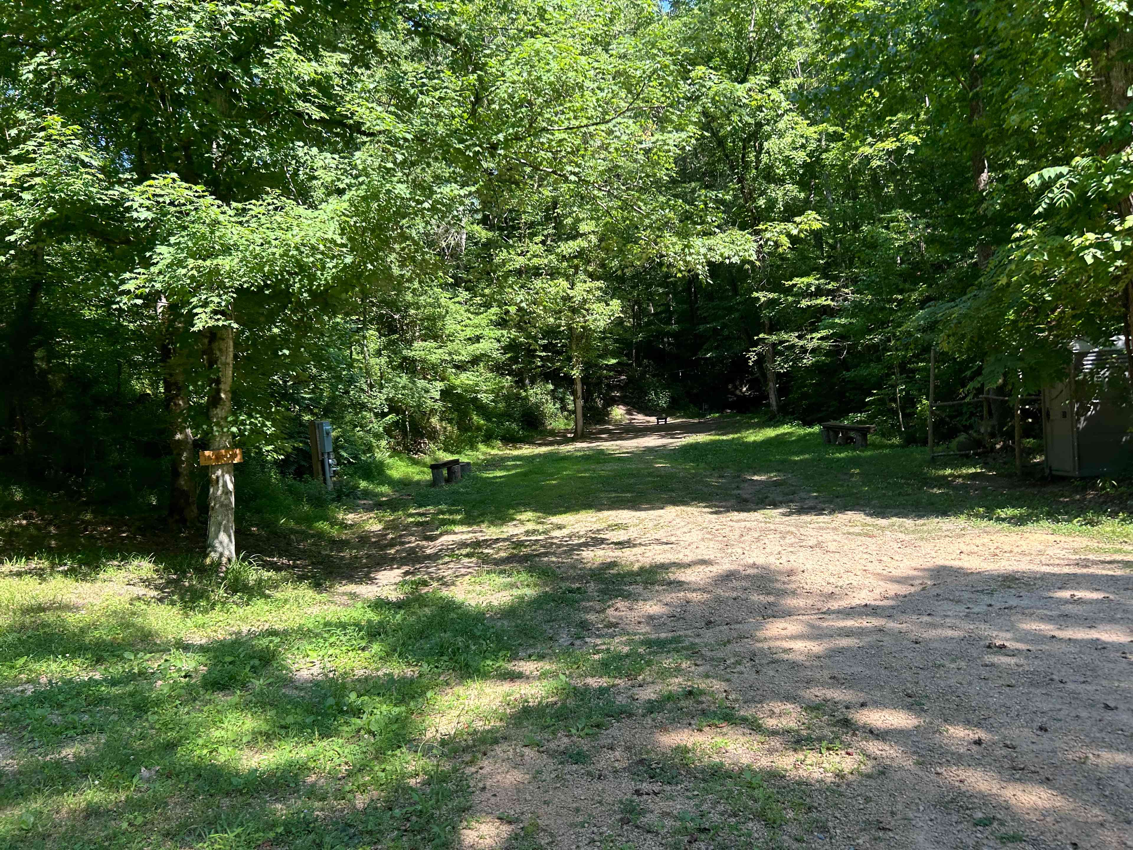 This campsite has plenty of room to pull up to the tent site. There is plenty of shade and spring water flows past on the right side. There are two chairs and a small table along with a raised fire pit. There is also a portable restroom located at this campsite. We do host weddings at this waterfall venue, but the benches will not be set up when you arrive, giving you plenty of room for an RV or multiple vehicles. Feel free to make yourself at home!