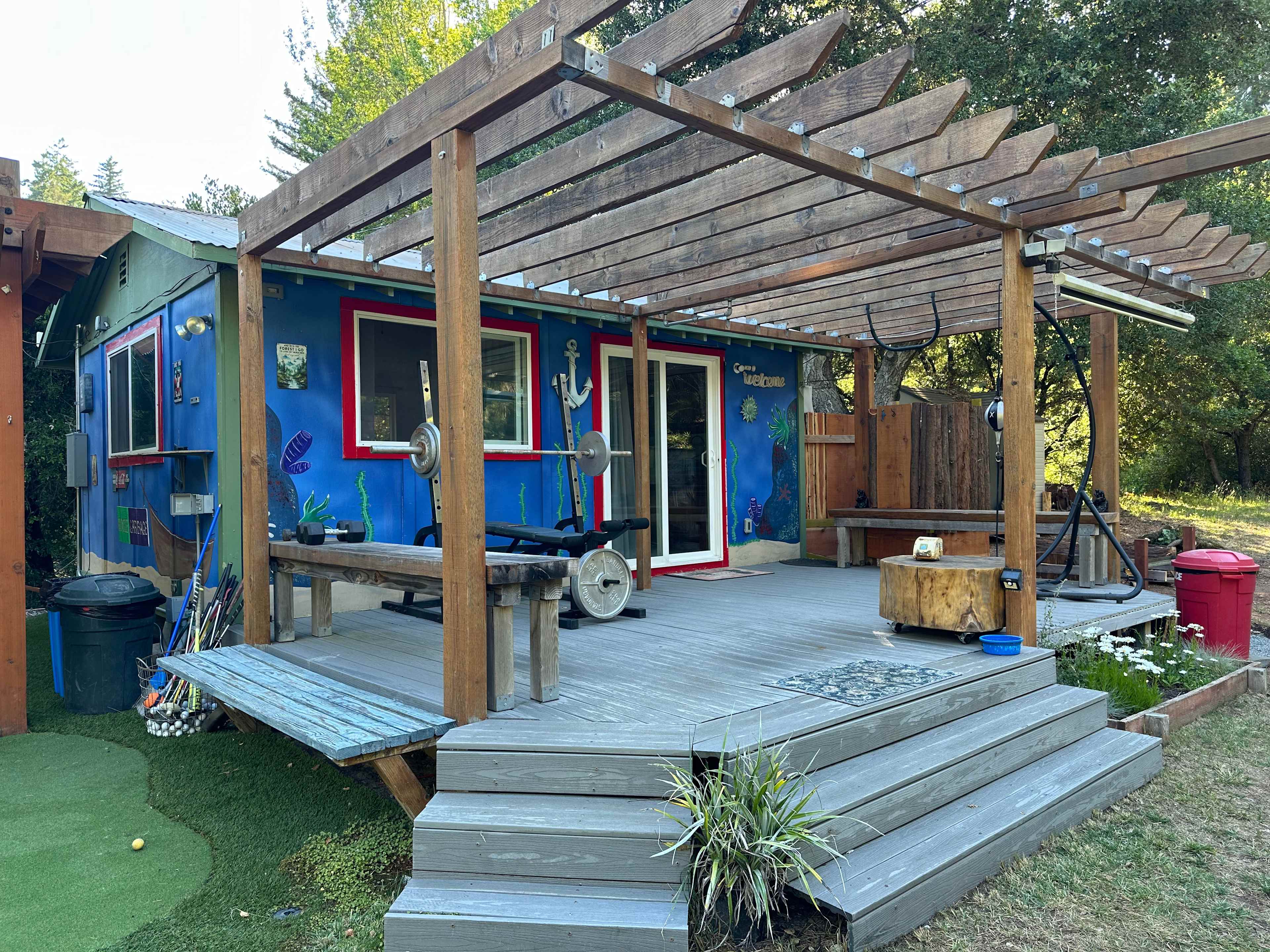 Bungalow porch with weight bench, punching bag, pull-up bar and shower. 