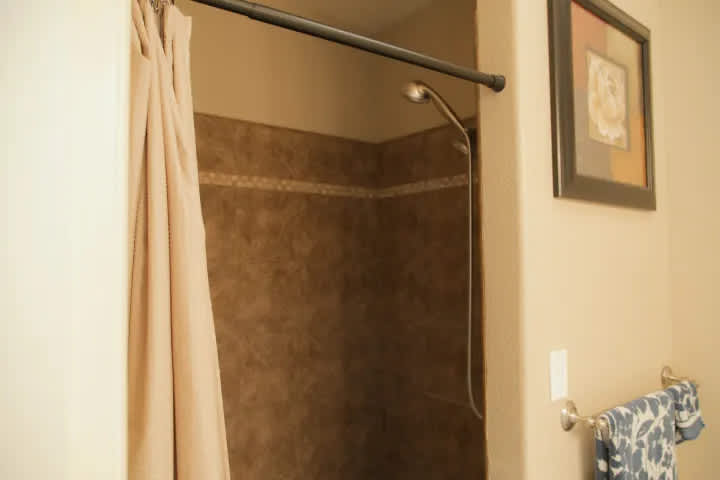Large shower, with two shower heads and bench to sit on. 