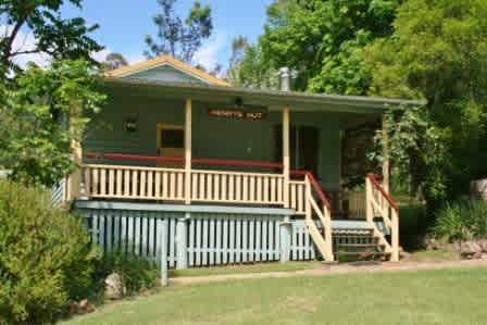 Front veranda of Henrys Hut with picnic table and 2 comfy lounge chairs.