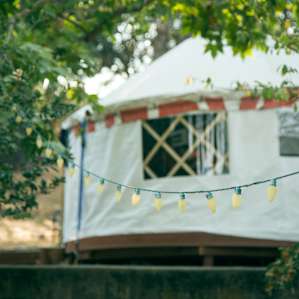 The yurt is nestled in a little forest, tangled up in whimsical holiday lights.