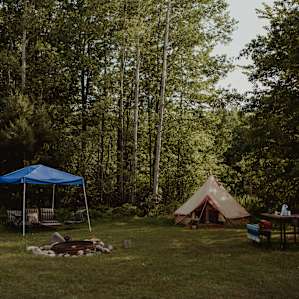 The full tent campsite, including table, firepit, and sitting area.