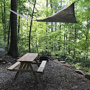 tarp over fire pit with picnic table at campsite