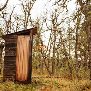 The outhouse with a lit path to it in the night.