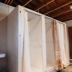 A view inside the bath house. There are multiple shower stalls available to campers with curtains for privacy.