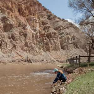 Dipping a finger in the Colorado River. It's brown this time of year due to the high water levels and runoff coming down from snowmelt from tributaries.