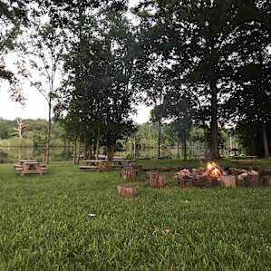 Large fire pit with a very large camp site next to the pond.