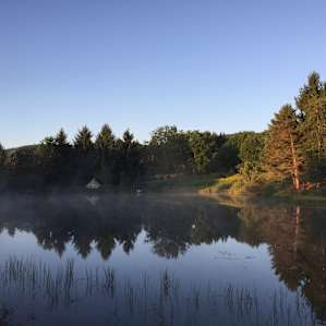 View of the campsite at sunrise from across the pond