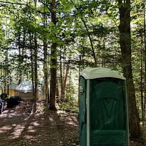 The port-o-potty with the tent site and tiny house in the background.