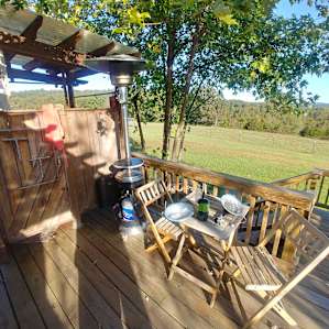 The shower room outside and a chair and table set on the deck