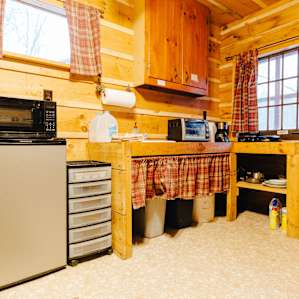 The kitchen inside the cabin, which includes pots, pans, cutlery, and a fridge.
