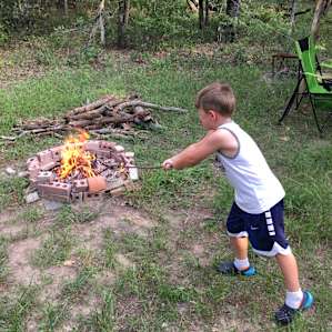 Noah learning how to tend to the campfire.