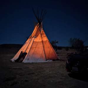 The tipi lit up at night from our campfire inside