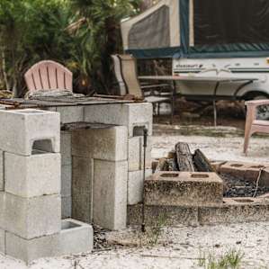 The campsite with the host's pop-up camper has a cool brick fire cooking space