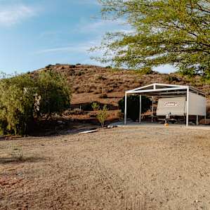 The RV is perfectly nestled under a shaded structure.