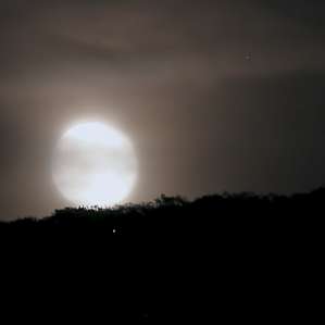 moon rising above the hills and thru clouds