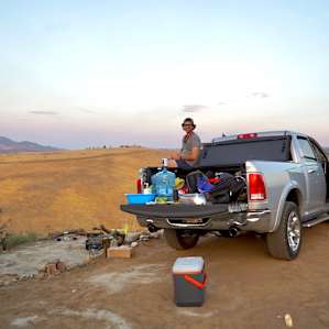Making dinner out of our truck bed, you can see our hand washing station and our camping “living room”, as well as our dog’s dining area. I believe we are facing south east and can see a sliver of the five in the distance. Big smiles all around.