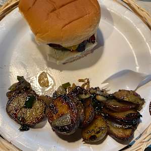 Bacon cheeseburgers and fried potatoes on the campfire.