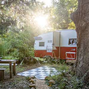 The cute retro camper called Towanda. The camper has a super comfortable bed, an eating space, a bathroom, and a kitchen with sink, stove and refrigerator.