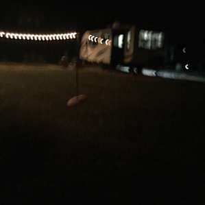 Beautiful lighted grassy area next to gravel pad.